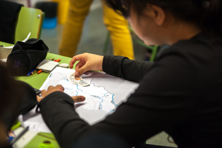 unja niña trabaja en su pupitre creando un mapa en papel con los ríos que pasan por allí