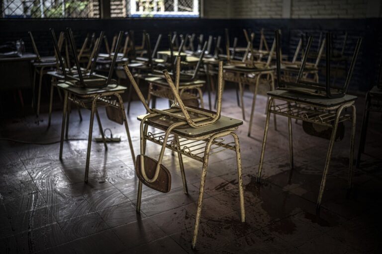 Imagen de un aula en la que las sillas están colocadas sobre los pupitres después de una sesión de clase