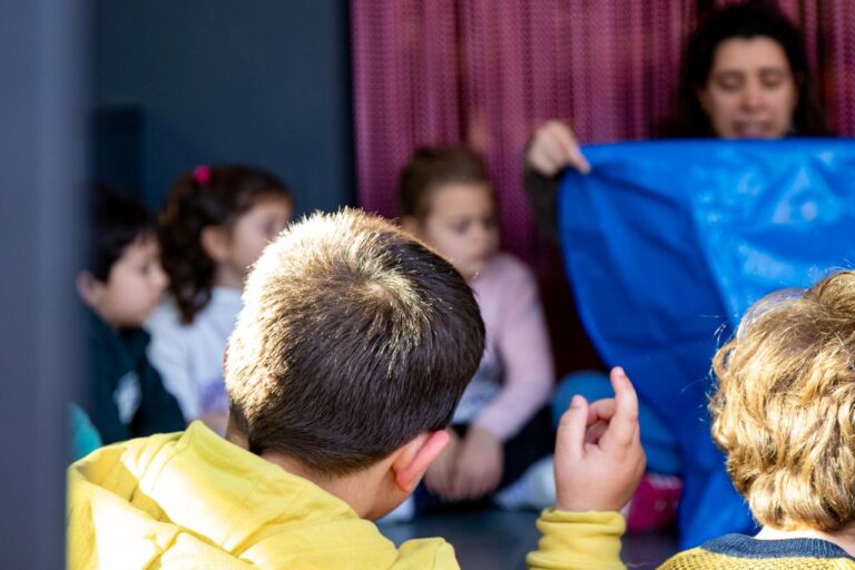 Un grupo de niñas y niños atienden a una actividad son su maestra