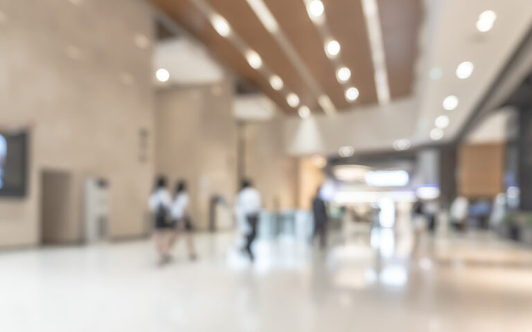 Blurred office building lobby or hotel blur background interior view toward reception hall, modern luxury lounge, white room space with blurry corridor and building glass wall