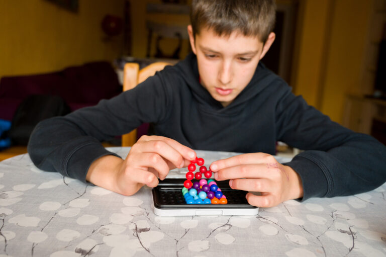 Teenage boy with autism focusing on assembling pieces game. Concept of autism rights movement. World Autism Awareness Day