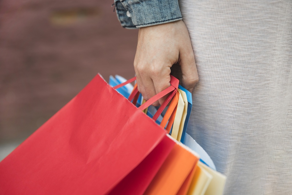 La mano de una mujer sostiene varias bolsas de papel de diferentes colores