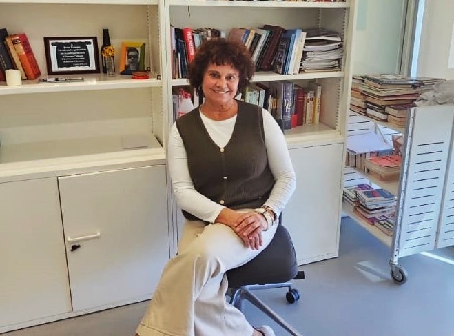 Rosa Ramón, gestora de la Biblioteca Pública del Estado en Ceuta, posa en el interior de la biblioteca rodeada de libros, símbolo del papel de las bibliotecas públicas en el fomento de la lectura y el aprendizaje a lo largo de la vida.